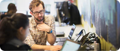 A man in glasses looking at a laptop.
