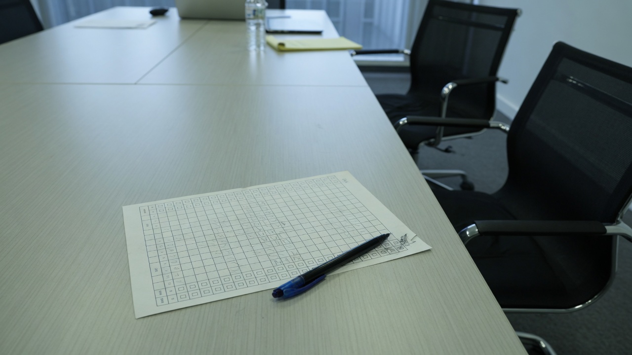 Printed scorecard on a conference table between empty chairs